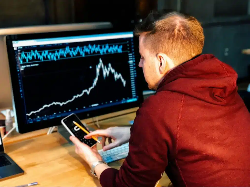 A man checks a stock chart on his mobile device, using Tiingo to access detailed data without limitations or extra charges.