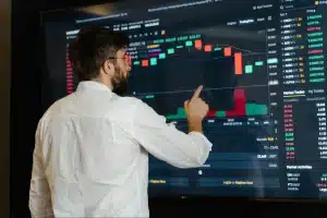 Person reviewing stock data on a large digital screen with charts and market details.